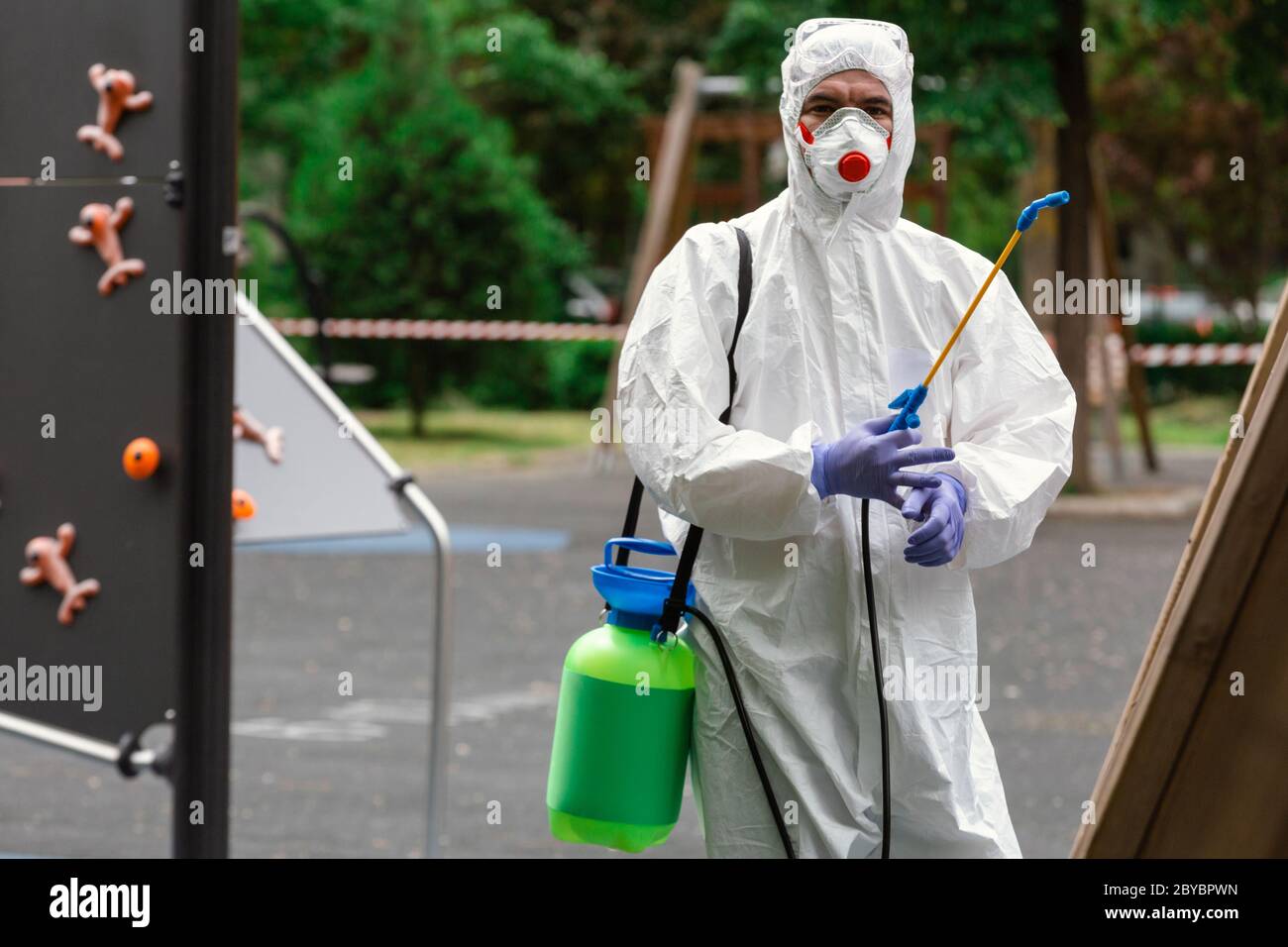 Ritratto di un uomo in un vestito medico protettivo che si prepara a disinfettare il parco giochi contro il coronavirus. Sanità pubblica. Foto Stock