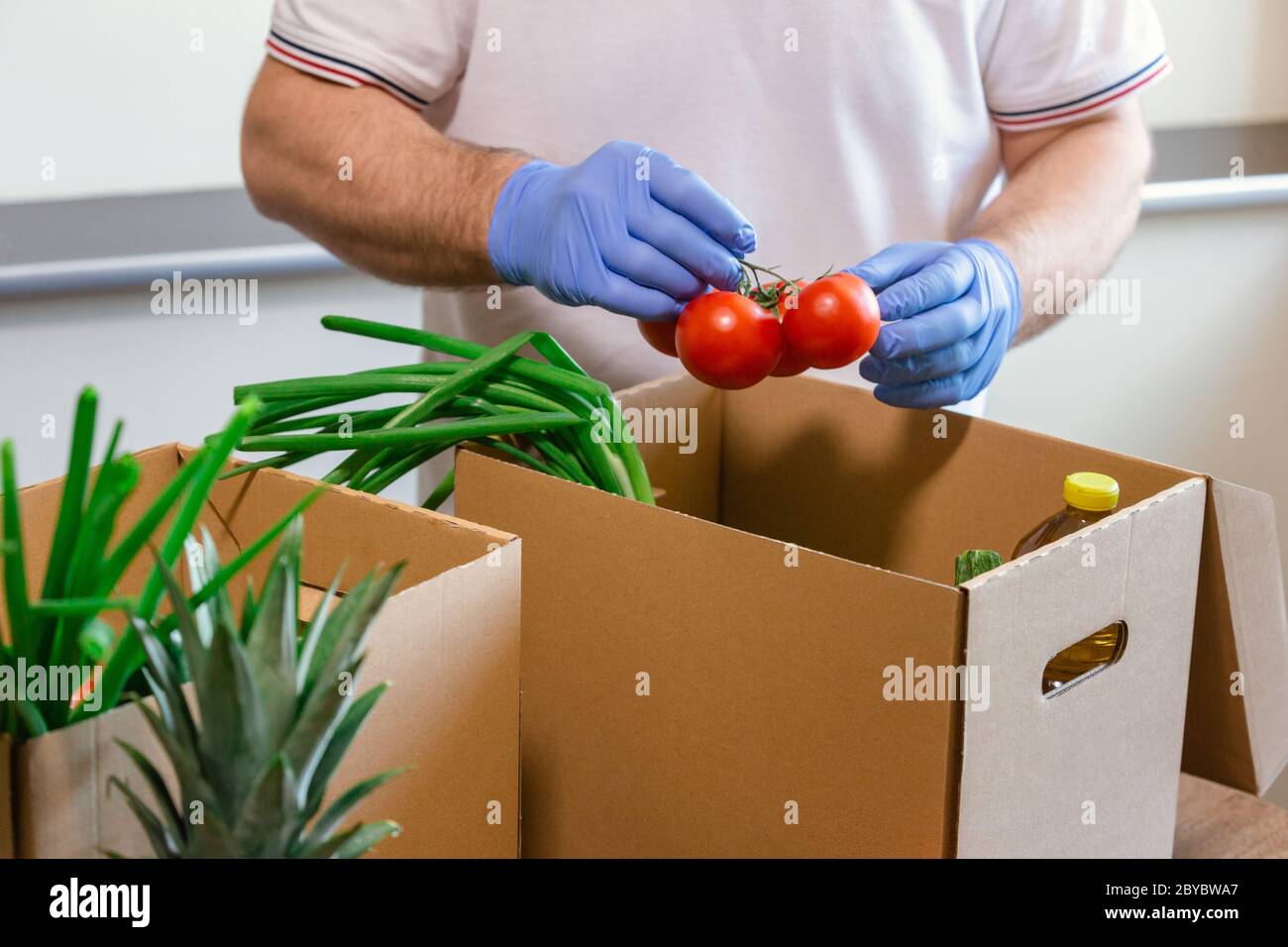 Fondi di soccorso e donazioni per il coronavirus. Volontari nella maschera medica protettiva e guanti per le mani Putting Food in Donation Box. Donazioni di beneficenza. Foto Stock