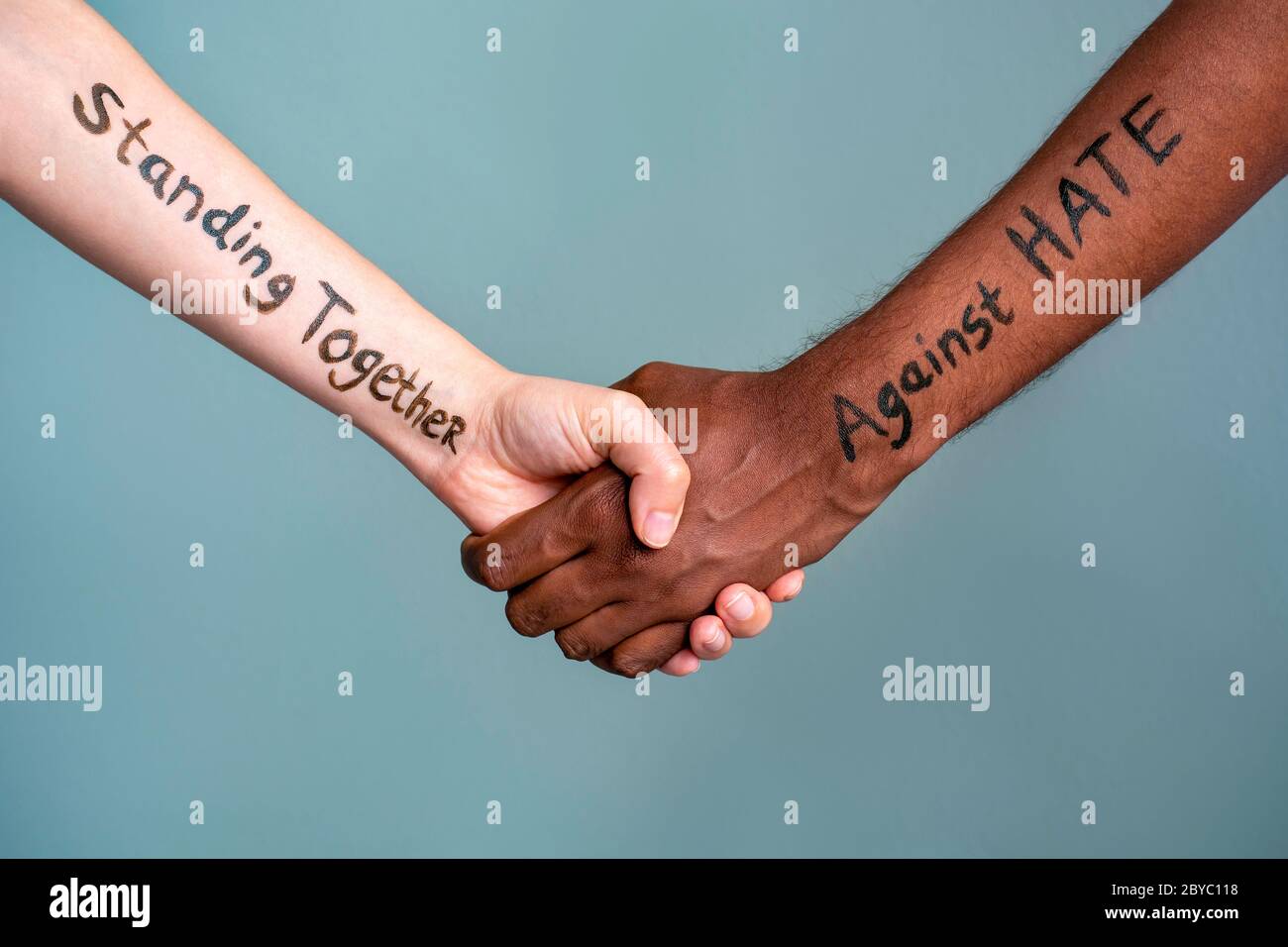 Stretta di mano tra la donna umana bianca e nera e le mani maschili con testo del messaggio stare insieme contro L'ODIO. Il concetto di Black Lives è una protesta Foto Stock