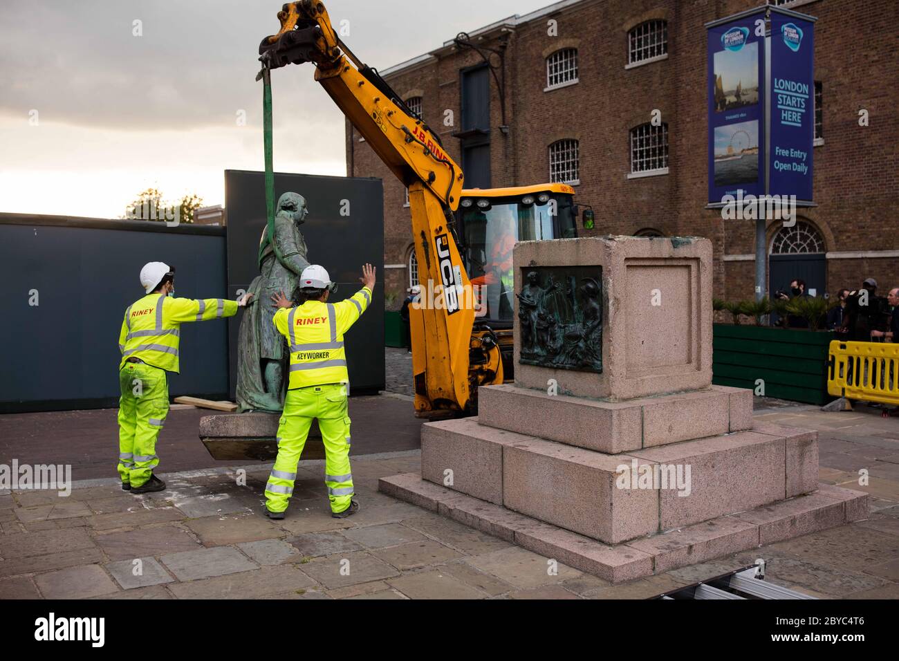 La statua di Robert Milligan viene sollevata dalla sua base utilizzando un JCB di fronte al Museo dei Docklands di Londra vicino a Canary Wharf. Foto Stock