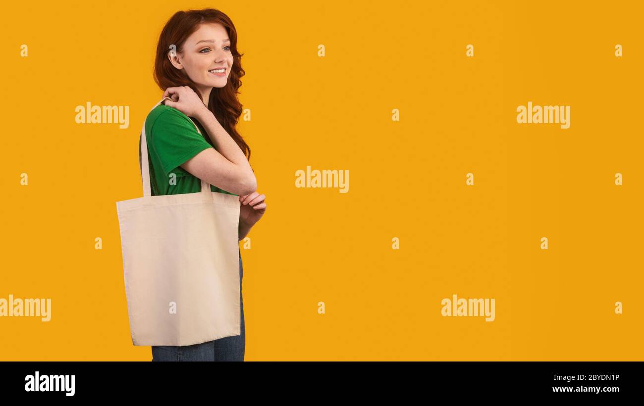 Ragazza con Flax Shopper Bag in posa su sfondo giallo, Panorama Foto Stock