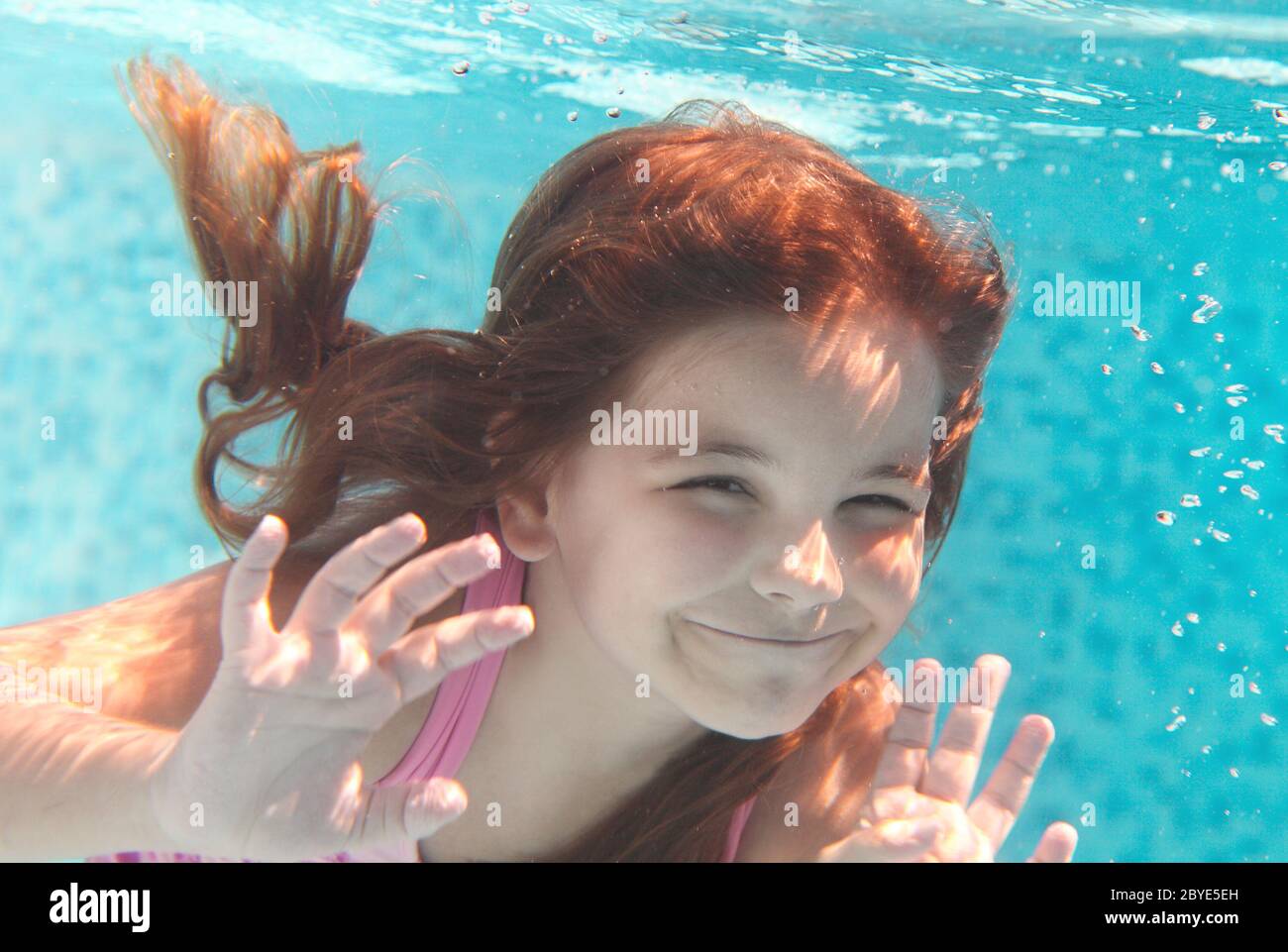 La bambina nuoto sott'acqua e sorridente Foto Stock