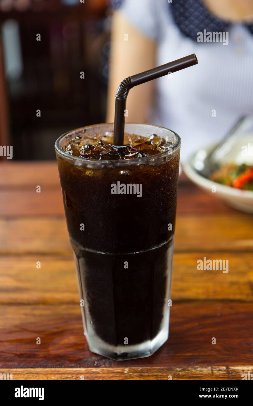 Caffè nero con ghiaccio su tavolo di legno, stile tailandese Foto Stock