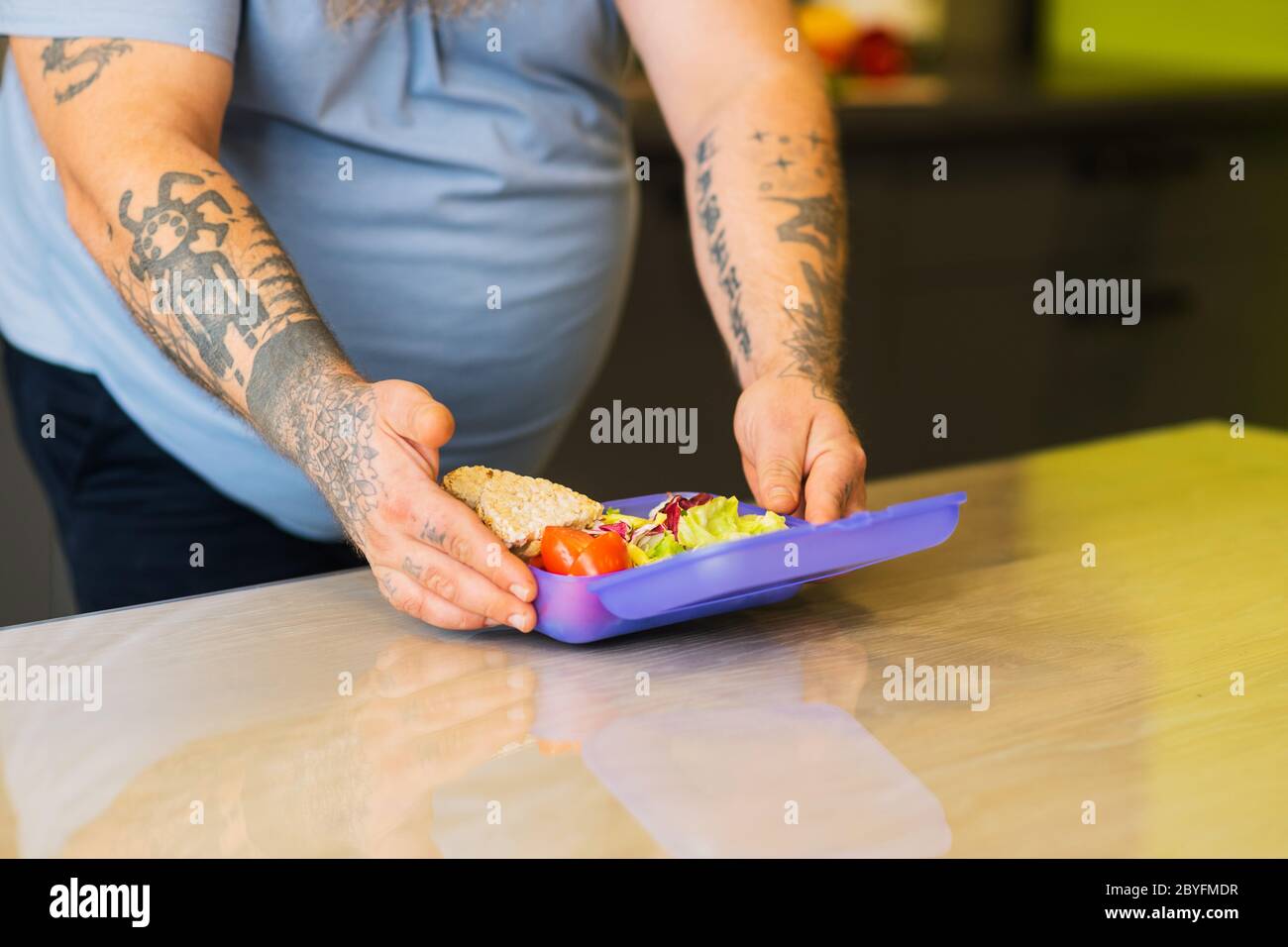 Mani maschili con tatuaggi che aprono la scatola portavalini viola sul tavolo Foto Stock