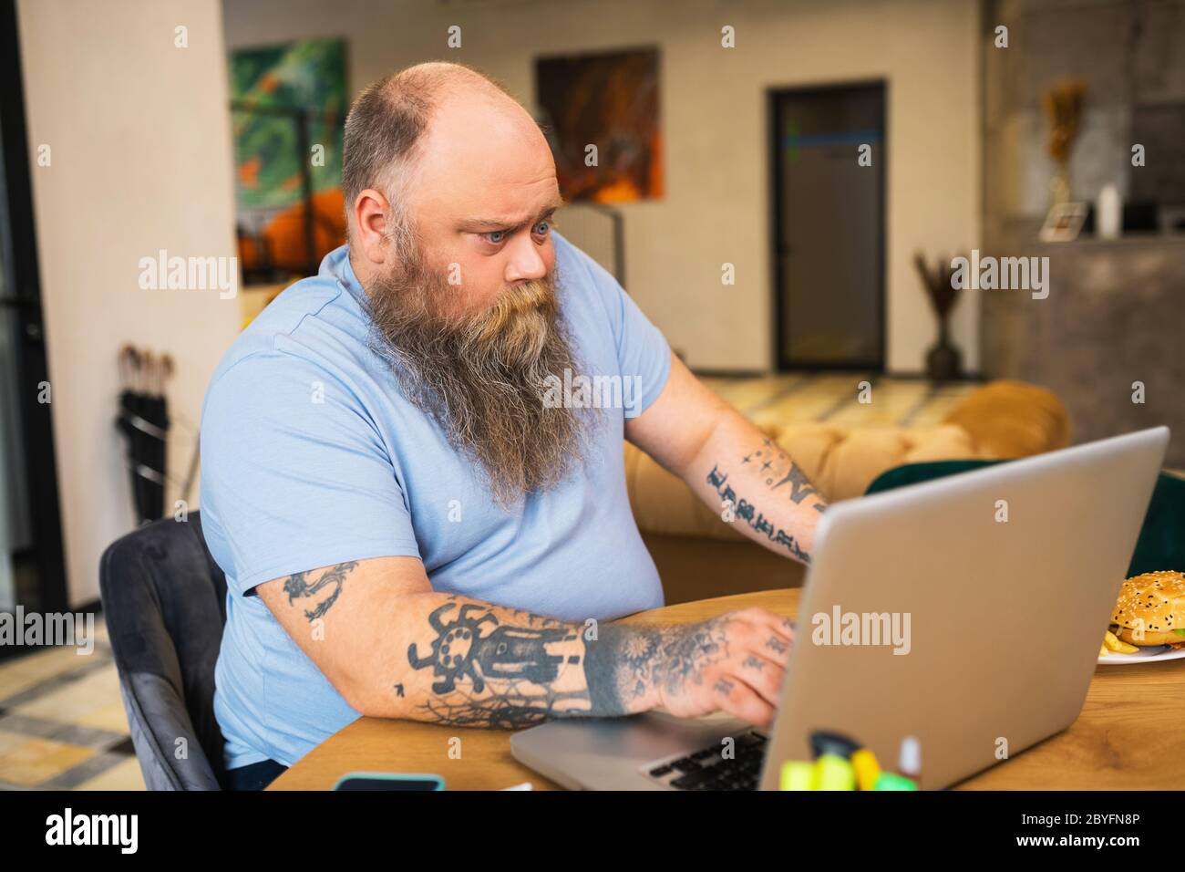 Uomo calvo che si siede su un computer portatile Foto Stock