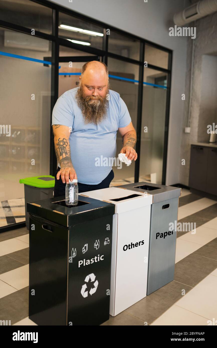 Lavoratore in ufficio sovrappeso che getta via rifiuti smistati. Foto Stock