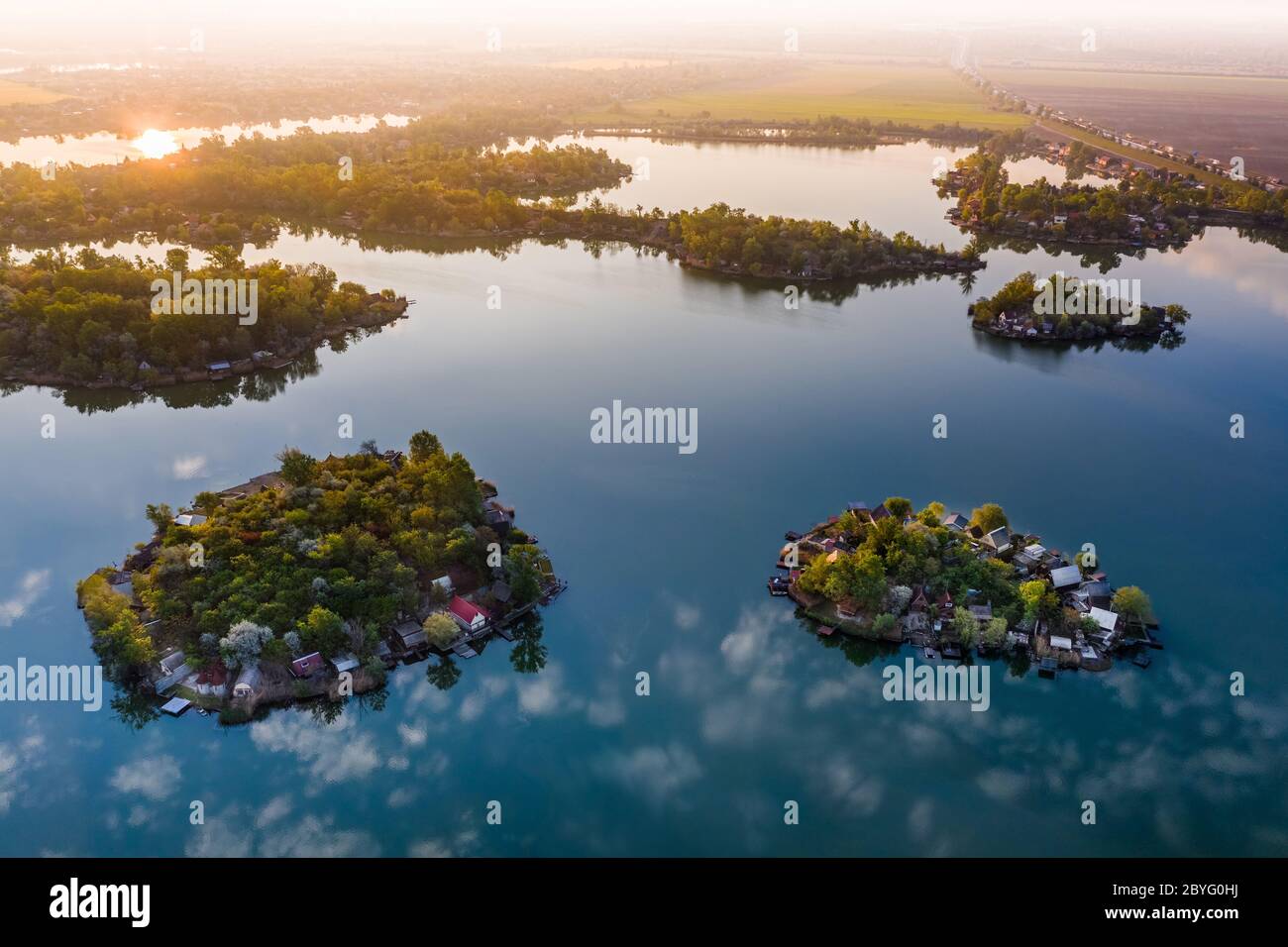 Budapest, Ungheria - Vista aerea delle piccole isole di pescatori sul Lago Kavicsos (Kavicsos to) del distretto di Csepel con un'alba calda e le nuvole riflettenti. Foto Stock