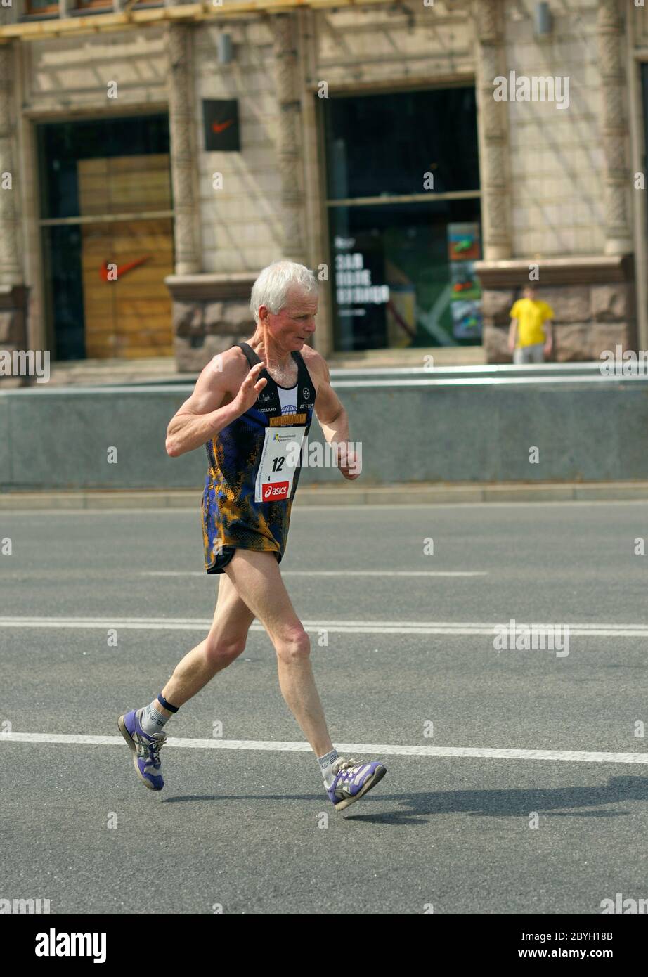 Un vecchio uomo in tuta che corre per strada. Maratona tra