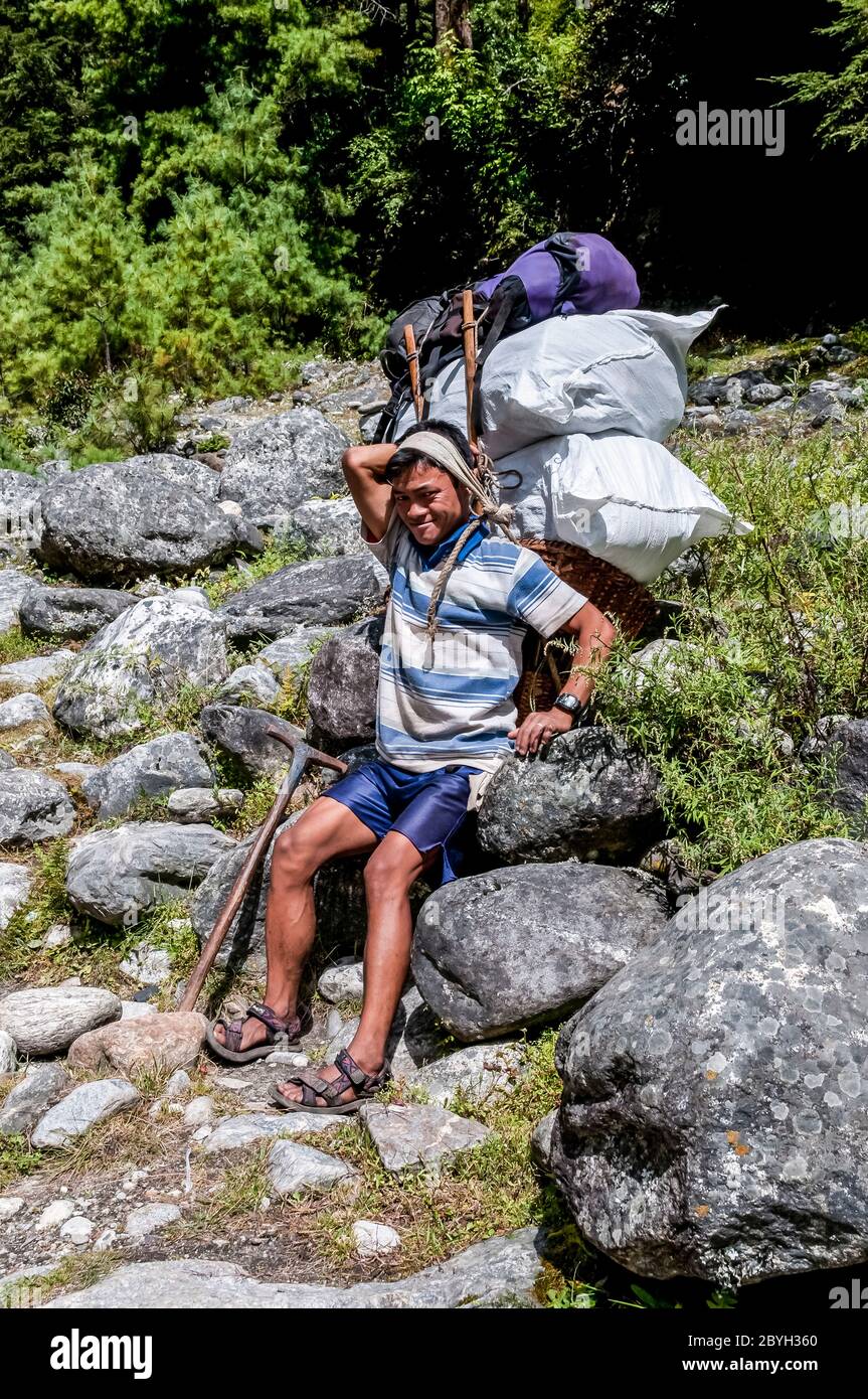 Nepal. Trekking di picco dell'isola. I portieri carichi di pesantemente fanno una pausa sulla loro strada per la città commerciale di Namche Bazaar Foto Stock