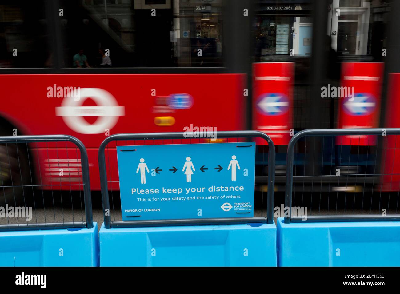 Mentre il blocco della pandemia di Conornavirus del Regno Unito continua, Ma con le restrizioni di viaggio e le regole di allontanamento sociale che iniziano a attenuarsi dopo tre mesi di chiusure e isolamento, un autobus di Londra si arrossisce oltre un segnale stradale di distanza sociale dove la strada è stata ristretta a favore di più ampi marciapiedi a Borough, il 9 giugno 2020, a Londra, Inghilterra. Foto Stock