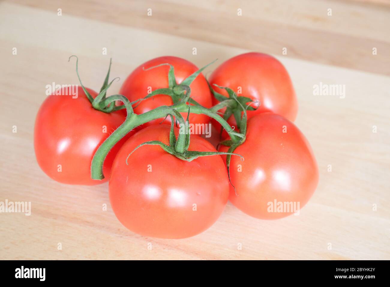 Pomodori chiamati grappolo tipo su tavola di legno, luce naturale Foto Stock