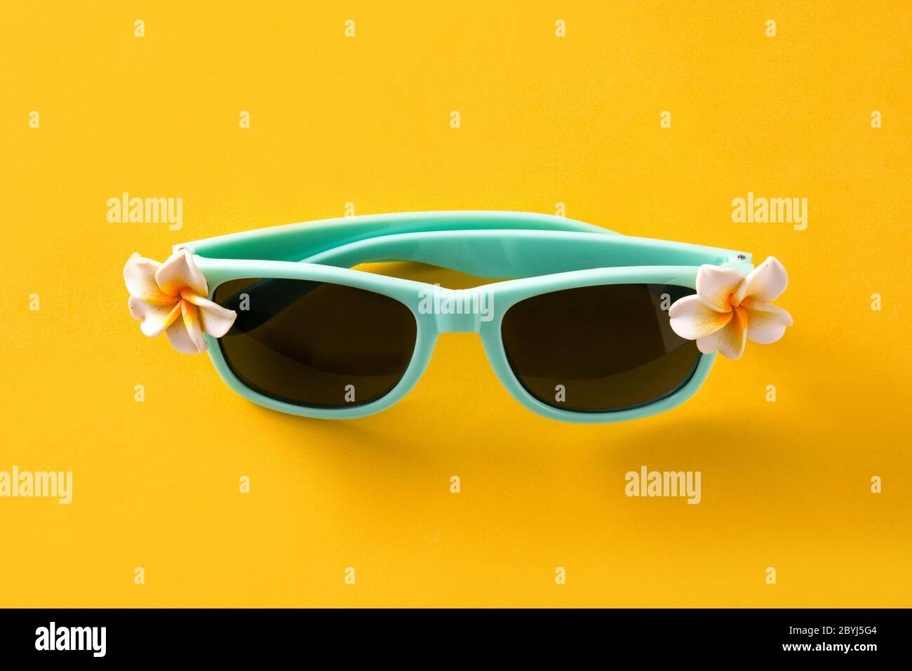 Occhiali da sole con fiori su sfondo giallo Foto Stock
