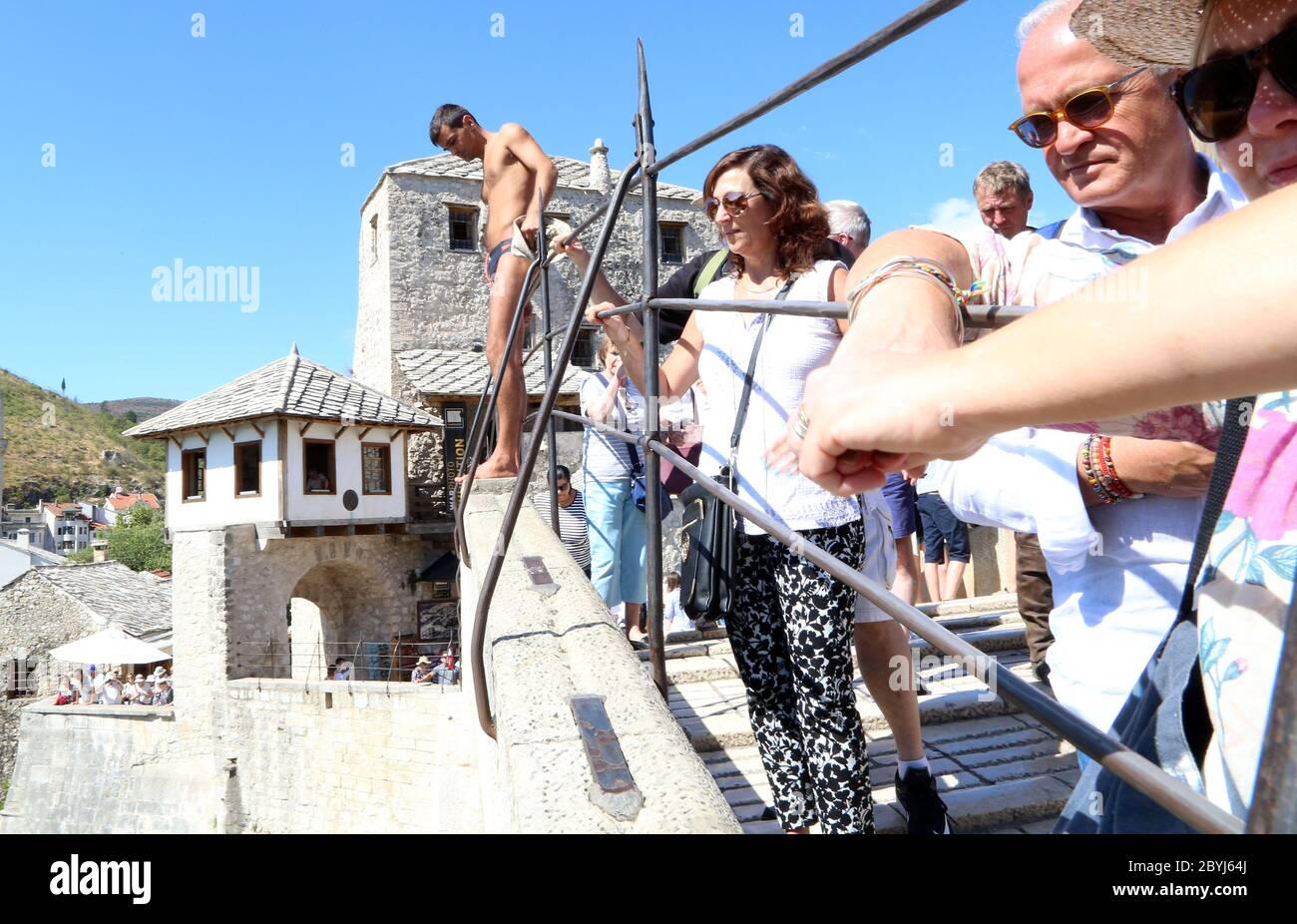 I subacquei di ponte aspettano il pagamento dai turisti per eseguire un salto di sfida di morte da un ponte a Mostar, Bosnia Erzegovina Foto Stock