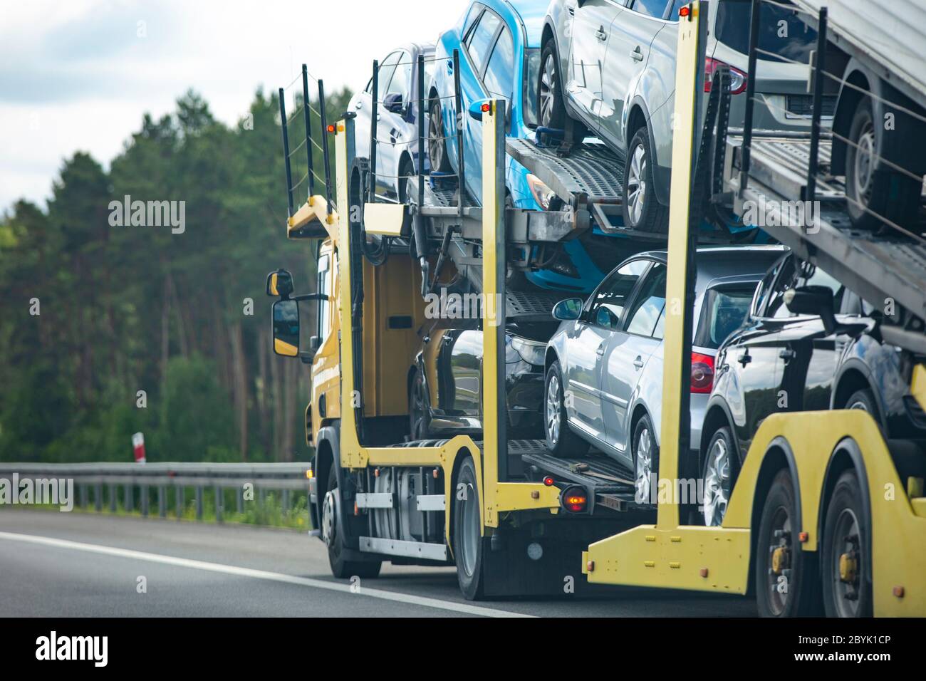 Rimorchio per auto con molte auto su autostrada, effetto di sfocatura del movimento. Foto Stock