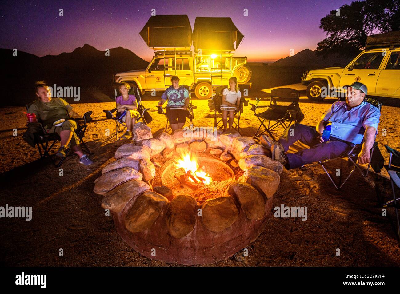 Tutti si riuniscono intorno al fuoco per un pasto caldo e un po' di relax, Helmeringhausen, Namibia Foto Stock