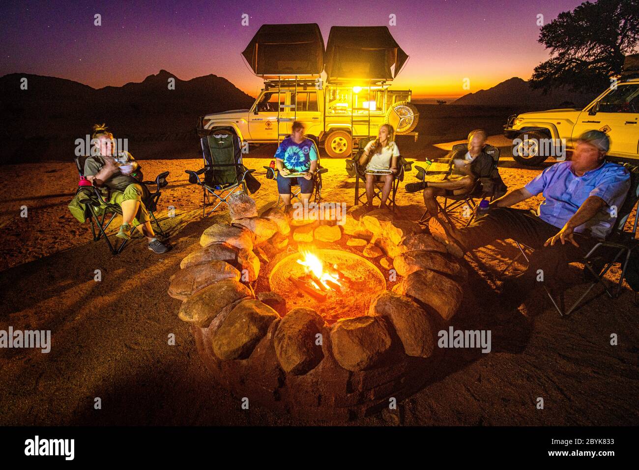 Tutti si riuniscono intorno al fuoco per un pasto caldo e un po' di relax, Helmeringhausen, Namibia Foto Stock