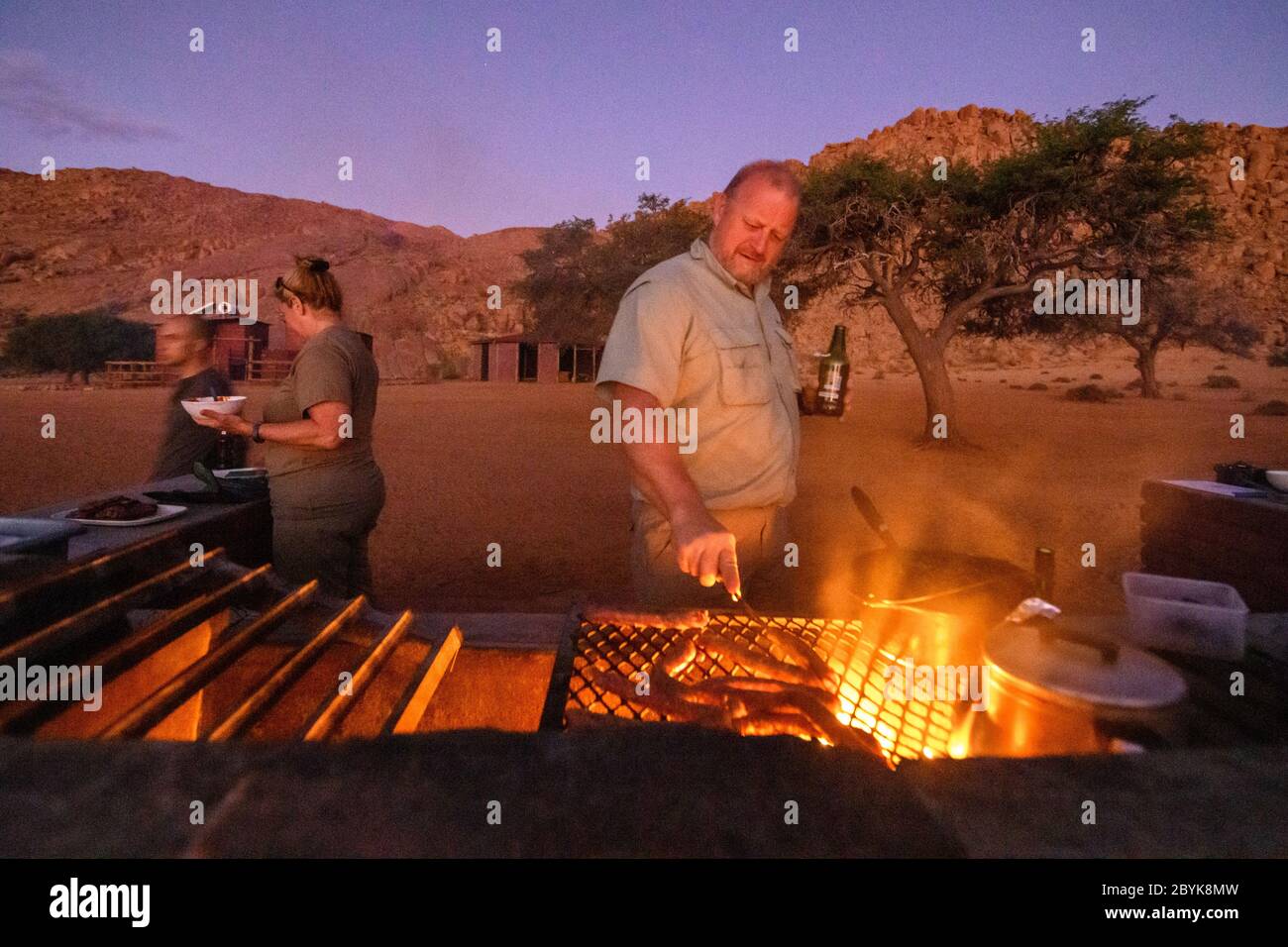 Un membro della festa di viaggio che cucinava del cibo per tutti, Helmeringhausen, Namibia Foto Stock