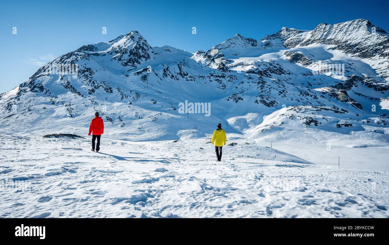 Due escursionisti in cima alla cima sopra la valle in montagna. Splendido paesaggio invernale delle Alpi svizzere durante una giornata di sole. Inverno all'aperto Foto Stock