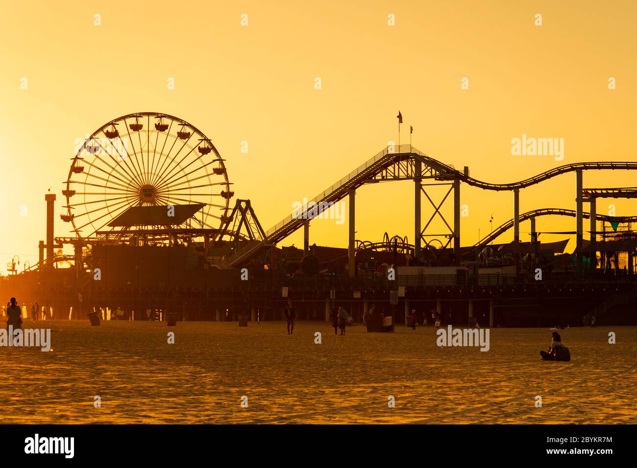 Molo di "Santa Monica" con ruota panoramica e montagne russe dalle silhouette che si contrappone al sole dorato. California, Stati Uniti d'America. Ott 2019 Foto Stock