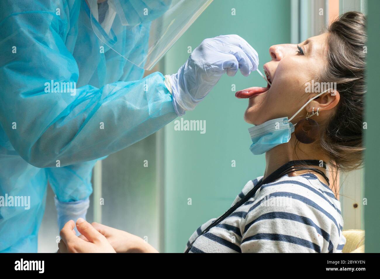 L'operatore sanitario con attrezzatura protettiva esegue il tampone del coronavirus sulla ragazza caucasica. Tampone per gola per Covid-19. Foto Stock