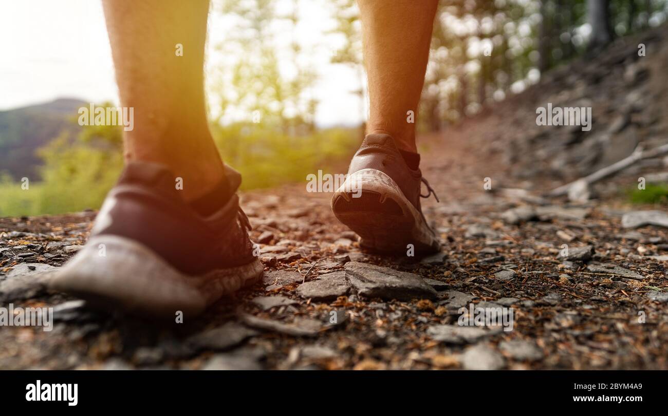 Primo piano gambe di corridore maschio, muscolo costruire uomo che corre veloce. Trail Runner che corre in montagna Foto Stock