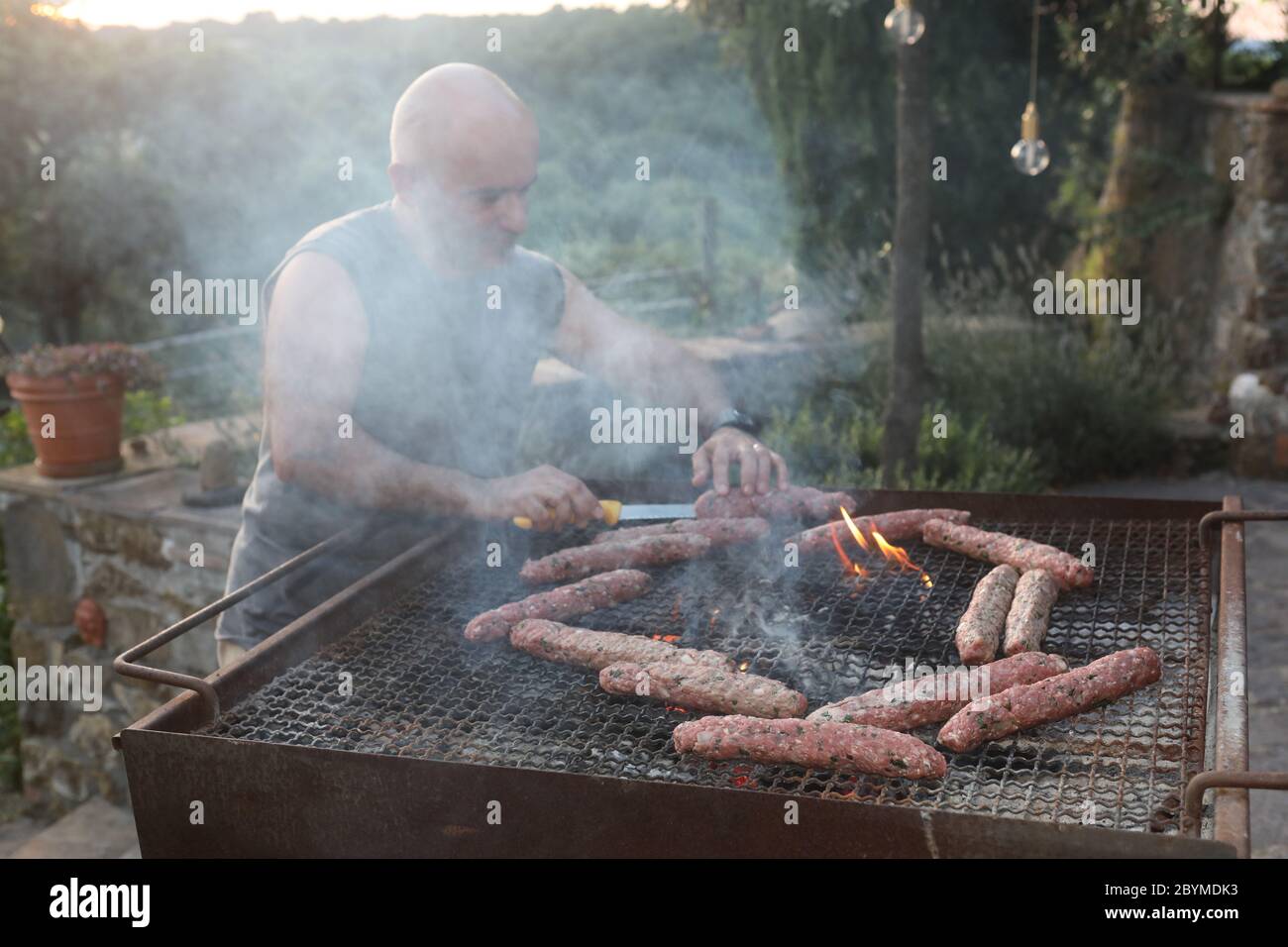 25.07.2018, Pomantello, Viterbo, Italia - uomo che prepara la carne alla griglia. 00S180725D086CAROEX.JPG [RELEASE DEL MODELLO: NO, RELEASE DELLA PROPRIETÀ: NO (c) caro imag Foto Stock