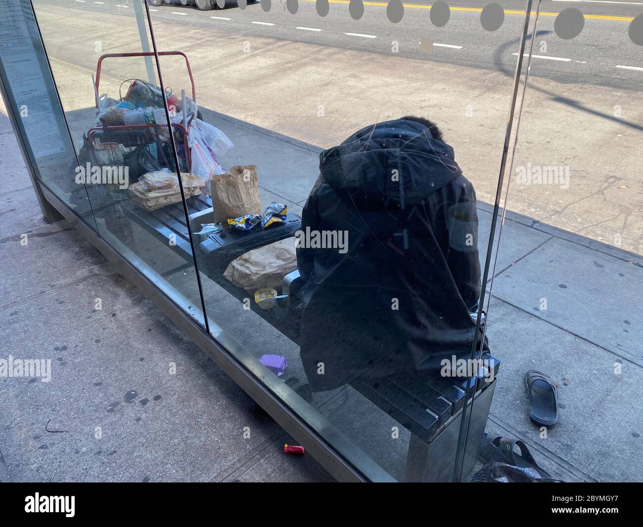 Senza tetto che ha allestito il suo spazio abitativo presso una fermata dell'autobus a Brooklyn, New York. Foto Stock
