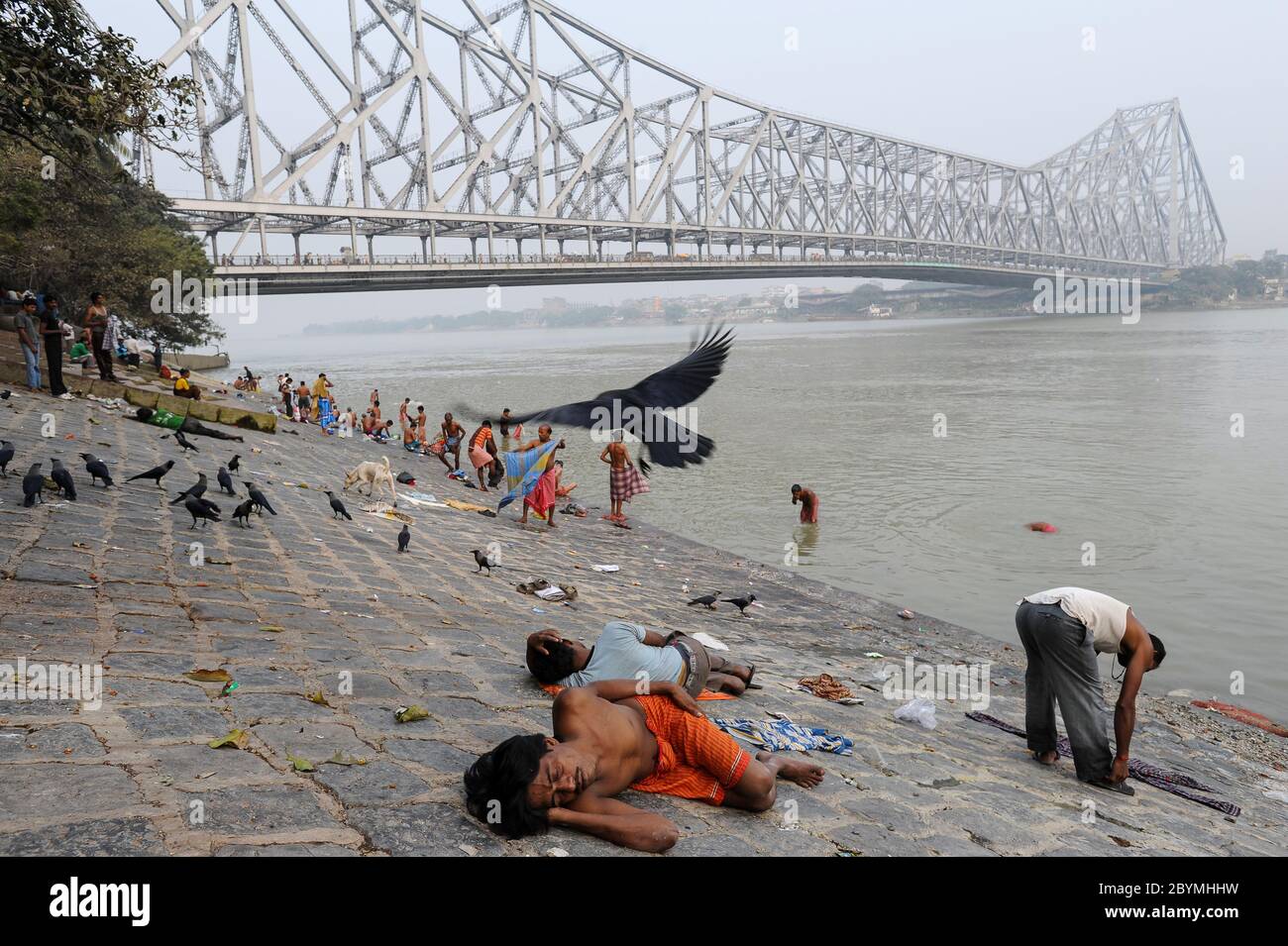 01.12.2011, Calcutta, Bengala Occidentale, India - la gente sulle rive del fiume Hugli con il ponte Howrah sullo sfondo, che collega i due cit Foto Stock