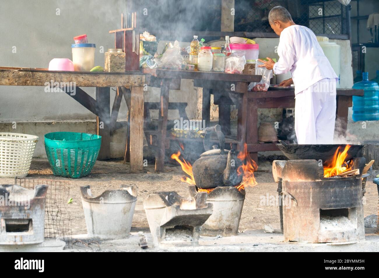 Suora in abiti bianchi che aiutano a preparare il cibo per i monaci buddisti. Foto Stock