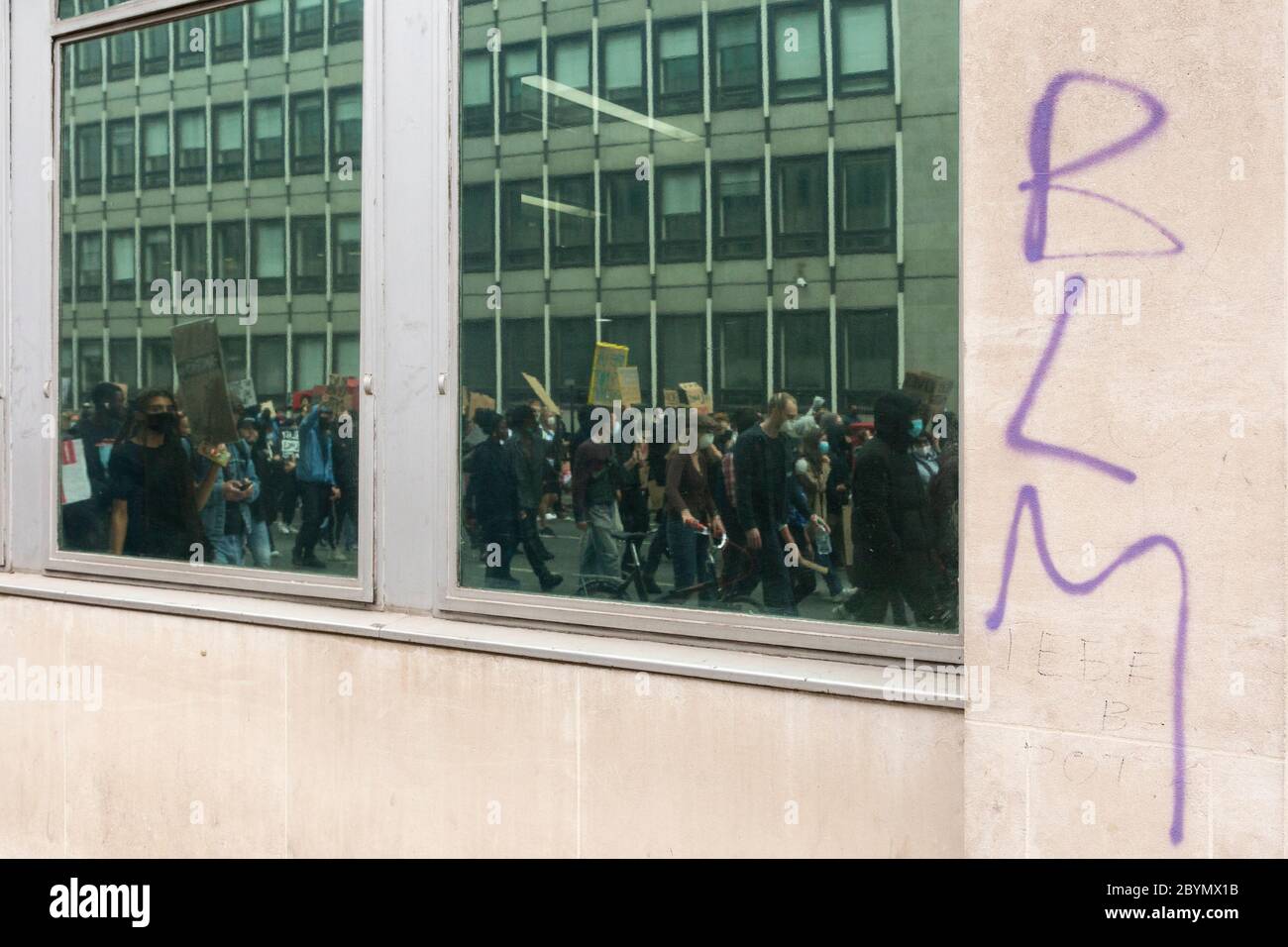 Graffiti su un muro con finestra riflesso di una folla di manifestanti che marciano durante una protesta Black Lives Matters, Londra, 7 giugno 2020 Foto Stock