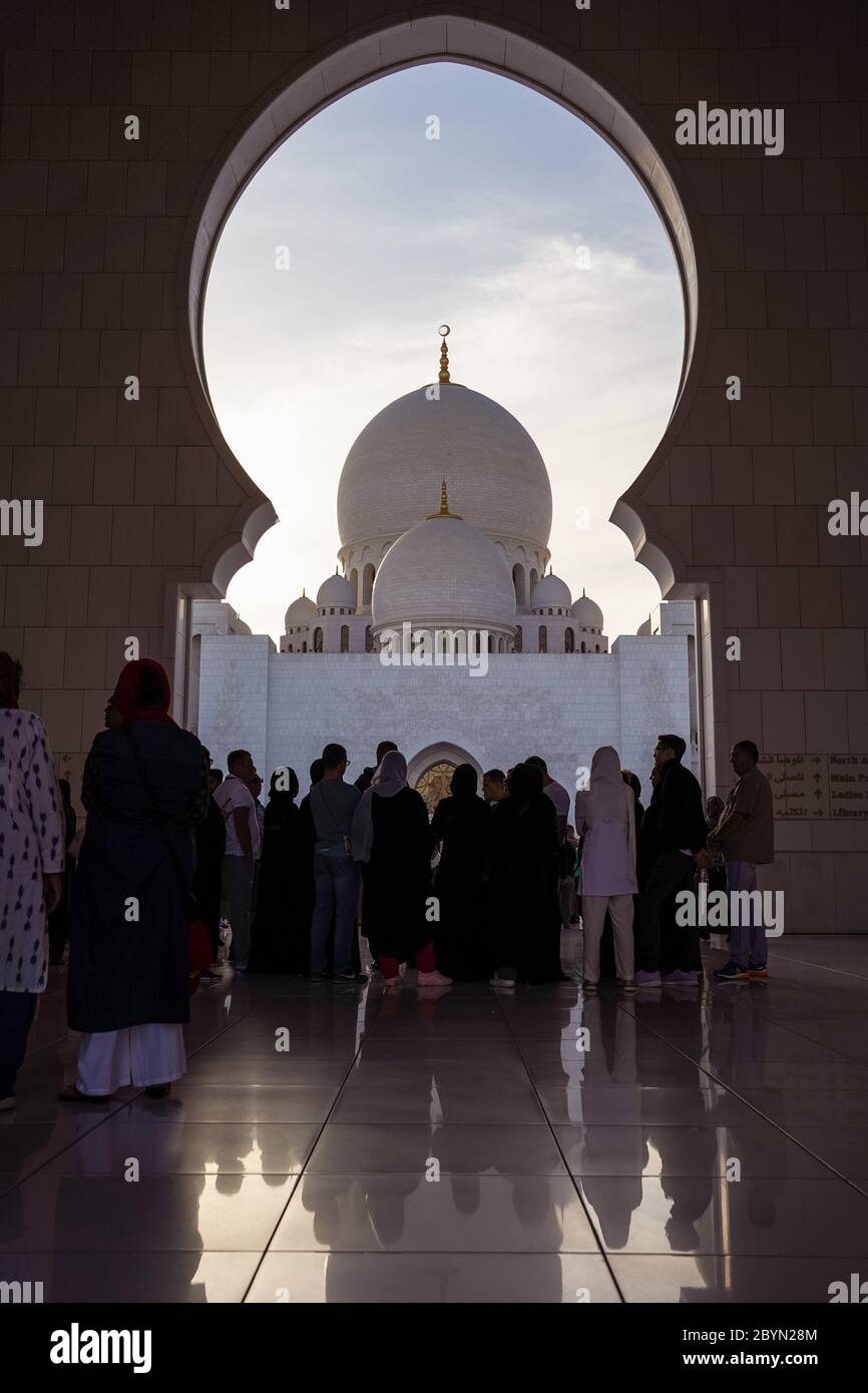 Abu Dhabi / Emirati Arabi Uniti - 5 febbraio 2020: Un grande gruppo di turisti sotto la porta ad arco nella Grande Moschea dello Sceicco Zayed Foto Stock