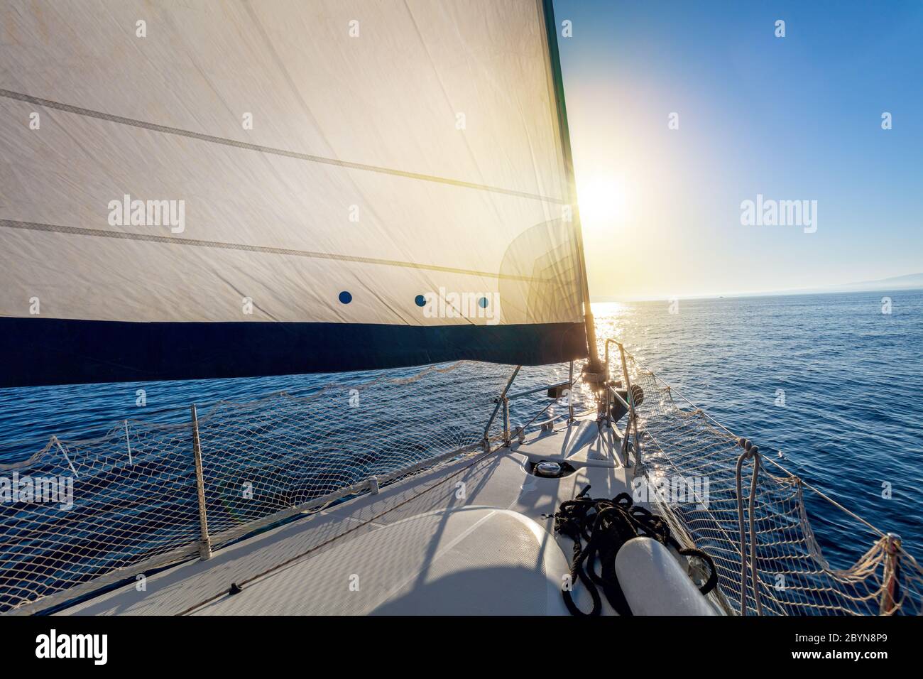 Vela a clima calmo con sole. Una vista dal ponte dello yacht alla prua e vele. Vela con vela a vela in mare aperto. Grecia, Europa Foto Stock