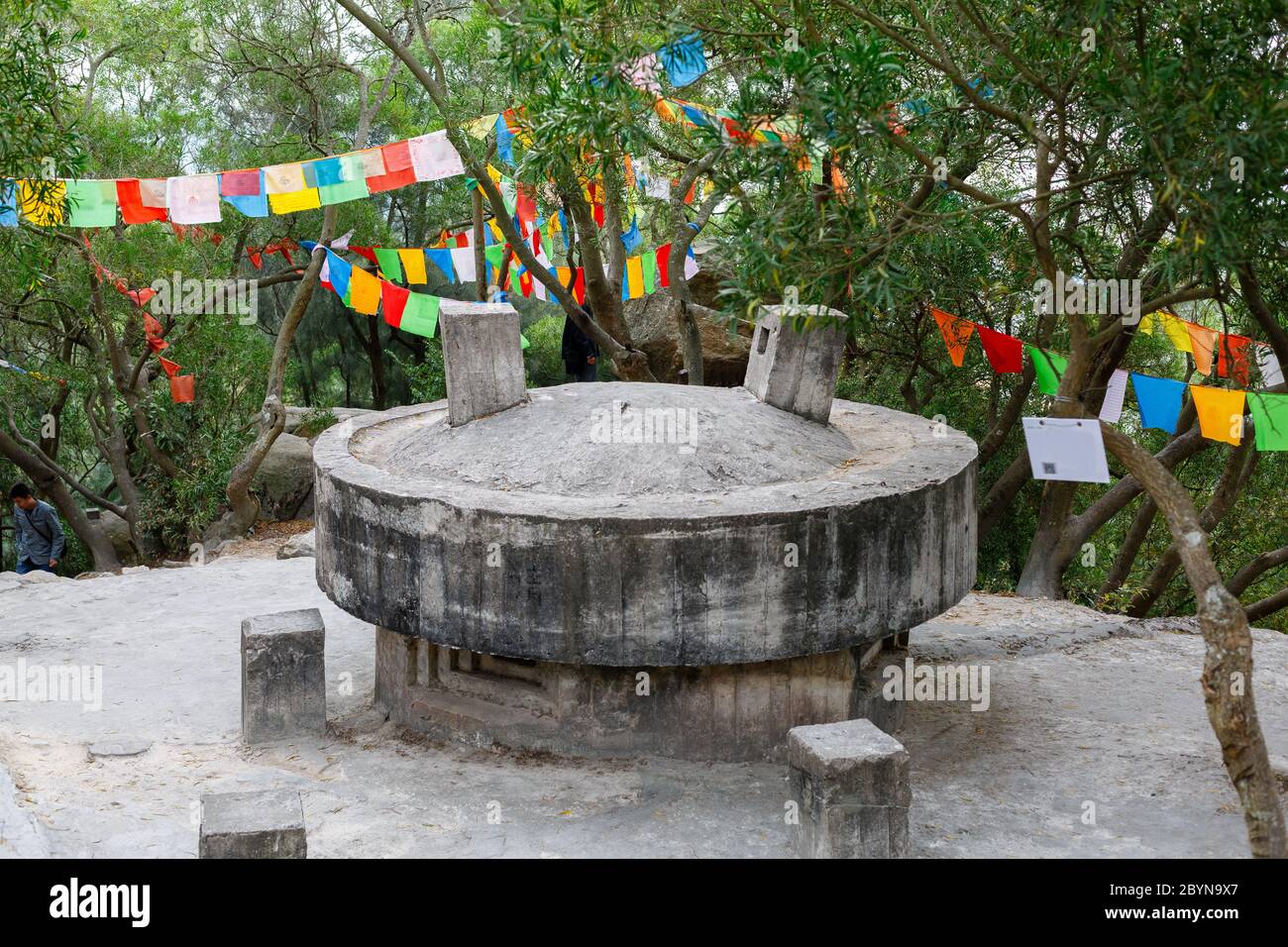 Bunker storico in cemento circondato da bandiere di preghiera tibetane. All'interno del parco del tempio buddista di Nantputuo. Foto Stock