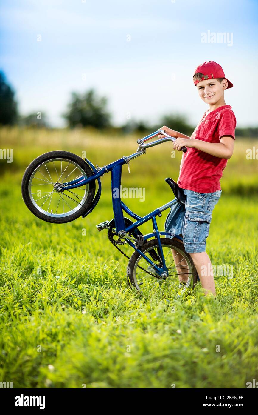 Giovane ragazzo in bicicletta equitazione in un parco Foto Stock