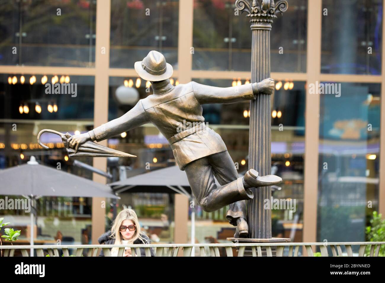 Statua di gene Kelly a Singing in the Rain, parte di una serie di sculture in bronzo a tema cinematografico in Leicester Square che celebrano un secolo di cinema Foto Stock