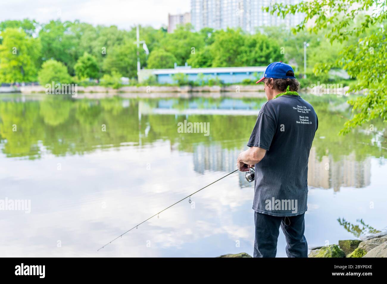 Manhattan, New York - 30 maggio 2020: Il pescatore getta la sua linea fuori dalle spiagge di Inwood Hill Park. Foto Stock