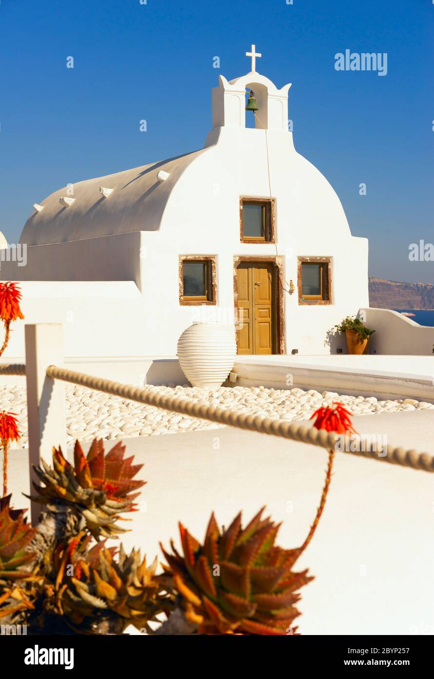 Piccola chiesa bianca con piazzale bianco nel villaggio di Oia a Santorini, Grecia, con vista sul Mar Egeo. Foto Stock