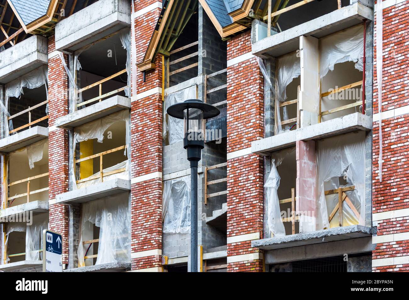 Strappato telo di plastica attraverso le aperture delle finestre sul cantiere mostrando danni da tempesta. Foto Stock