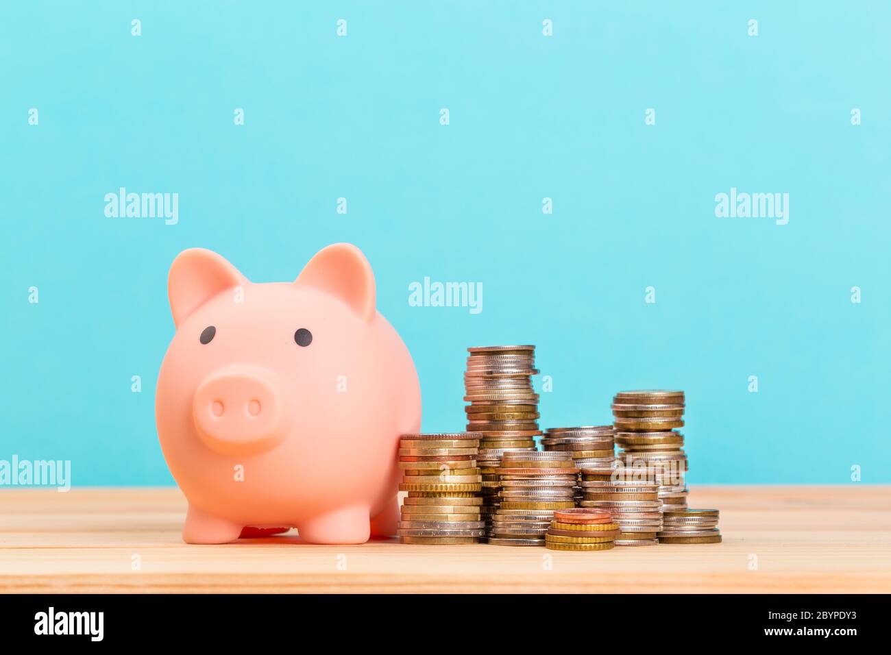 Banco di piggy rosa su tavolo di legno e sfondo blu. Il concetto di stoccaggio, accumulo. Crisi, inflazione, collasso finanziario. Foto Stock