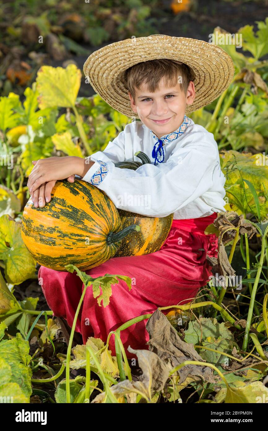 Ragazzo sorridente che tiene in mano una grande zucca gialla Foto Stock