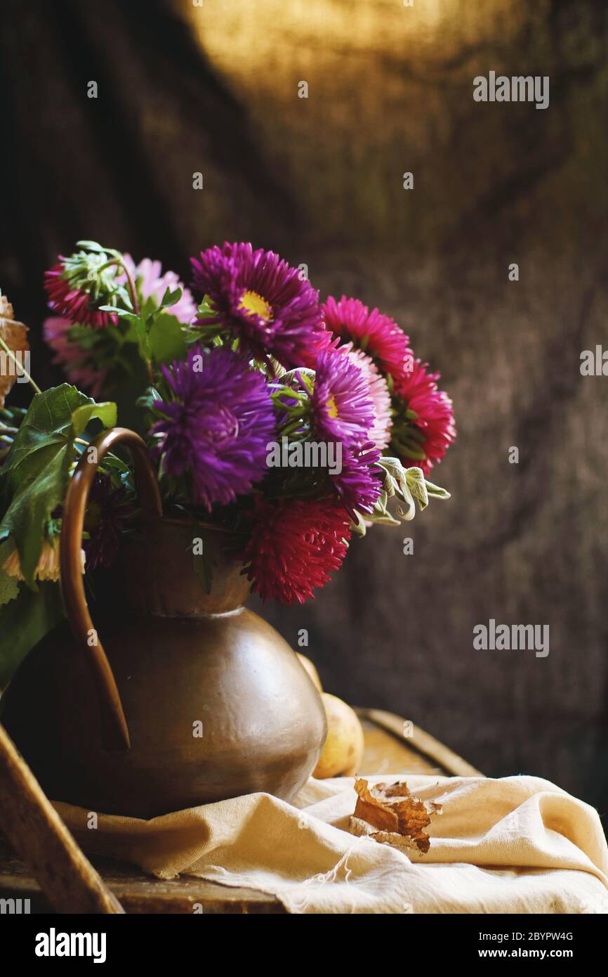 Un bouquet di aste in una brocca di rame su uno sfondo di tessuto. Foto Stock