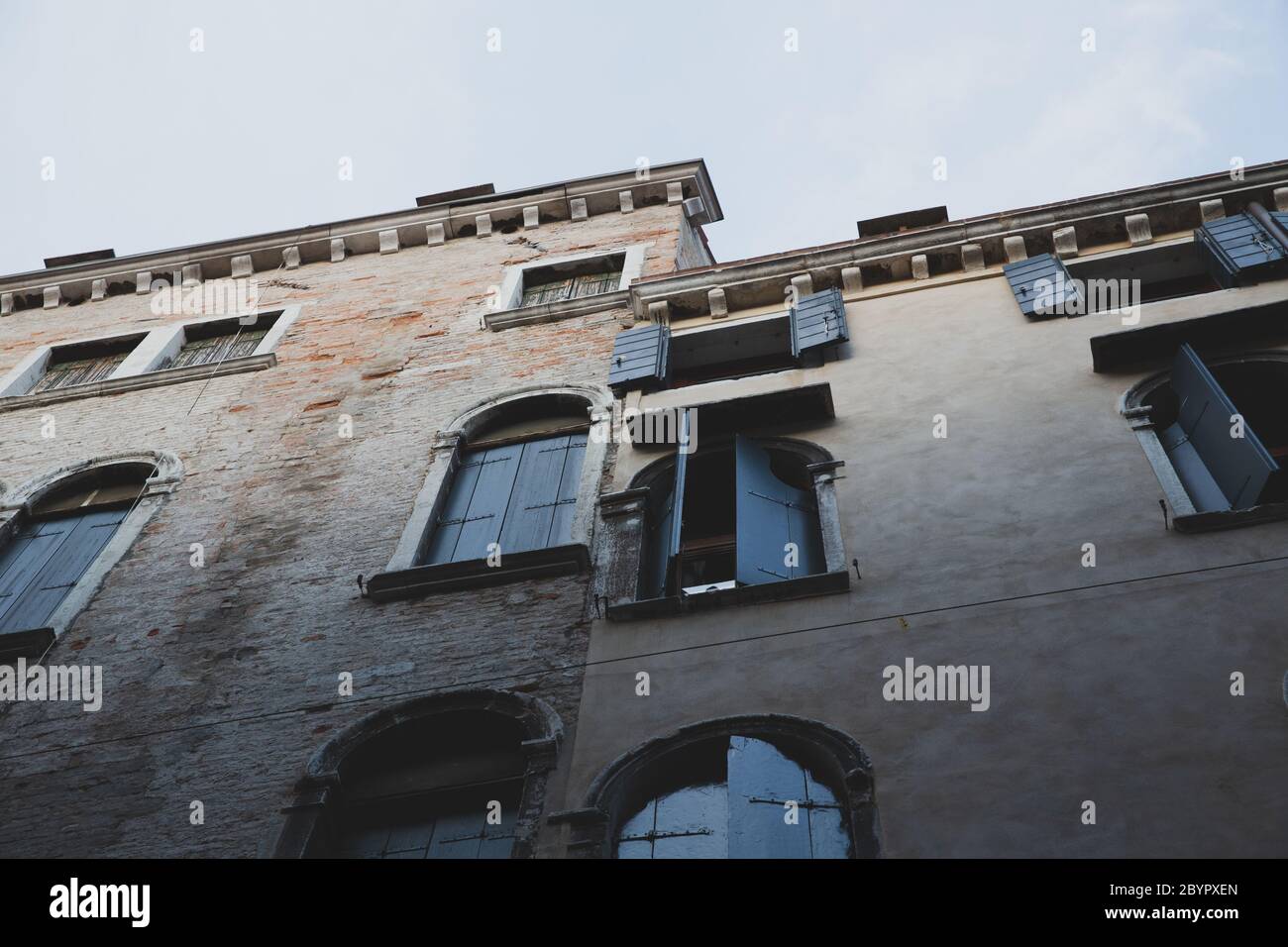 Facciata di un antico edificio veneziano in mattoni con una finestra aperta e un cielo blu chiaro, Venezia, Italia Foto Stock