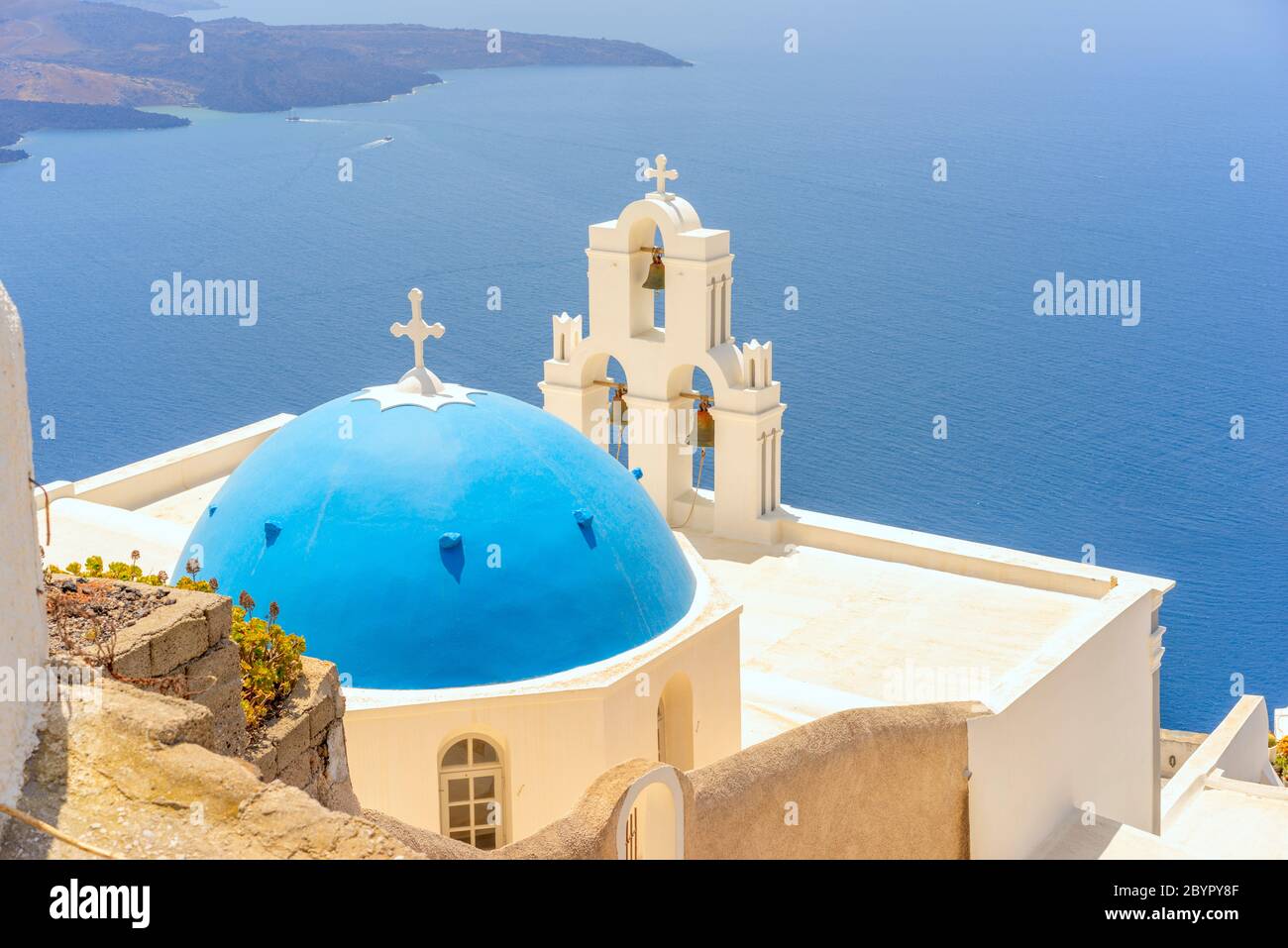 La Chiesa Cattolica della Vergine Maria a cupola blu e le tre campane di Fira sull'isola greca di Santorini, che si affaccia sulla caldera e sul mare Egeo Foto Stock