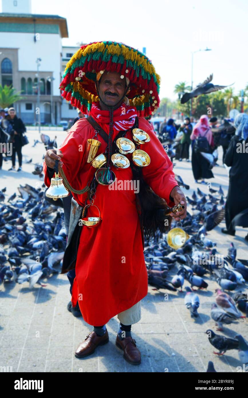 Uomo marocchino, vestito in rosso e con ‘krakebs’ (cimbali attaccati con una corda), coppe di ottone e cappello fiorito (zuhur qabea) pone per i turisti io Foto Stock