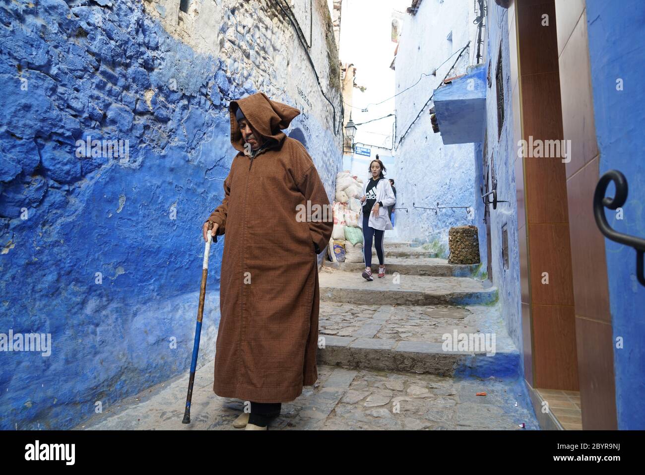 Un vecchio uomo che indossa la djellaba cammina nel vicolo della città unica dipinta di blu di Chefchaouen, originariamente conosciuta come Chaouen, che significa 'picchi'. Moula Foto Stock