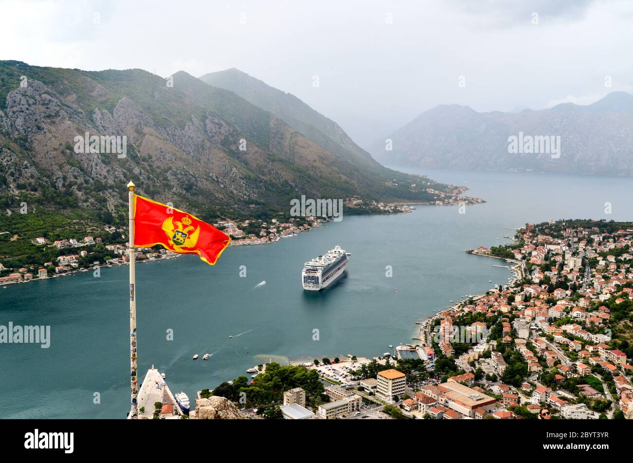 Bandiera montenegrina e grande nave da crociera nella baia di Kotor, Montenegro Foto Stock