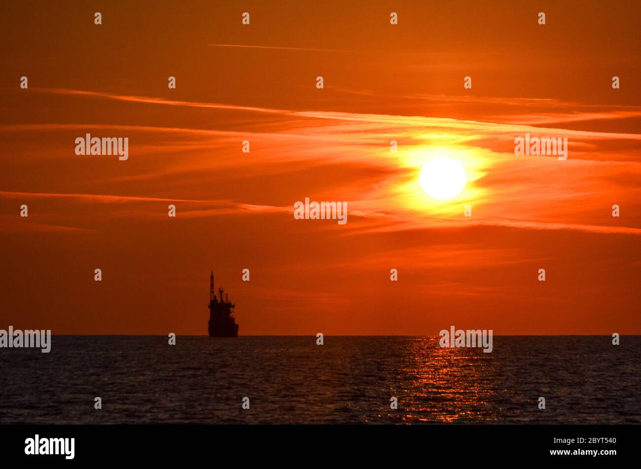 Tramonto sulla spiaggia di Bar, Montenegro, con una nave sotto il sole giallo Foto Stock