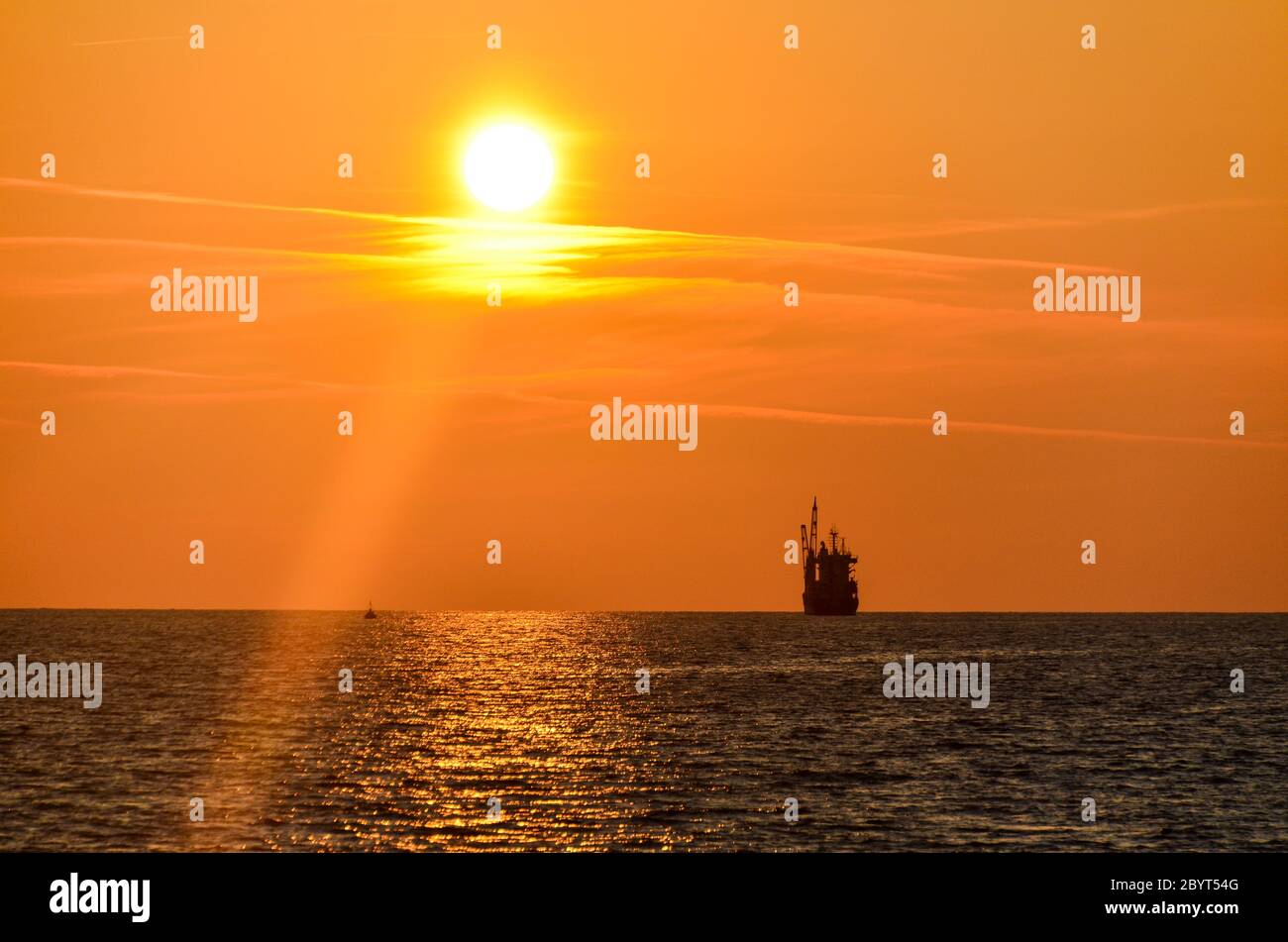 Tramonto sulla spiaggia di Bar, Montenegro, con una nave sotto il sole giallo Foto Stock