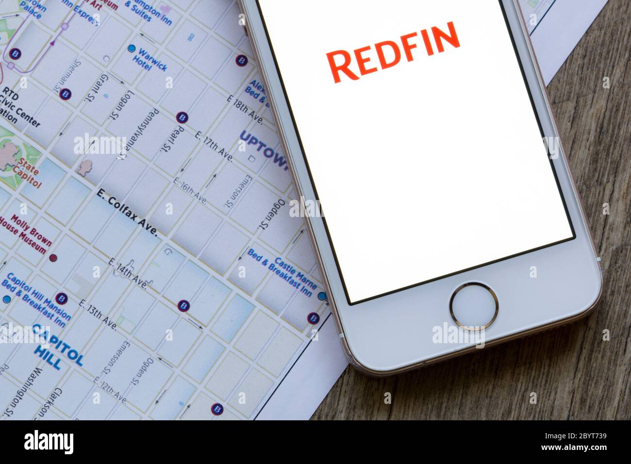 La pagina di benvenuto dell'app mobile Redfin viene visualizzata su uno smartphone sullo sfondo della mappa della città. Redfin è una società di brokeraggio immobiliare con sede a Seattle. Foto Stock