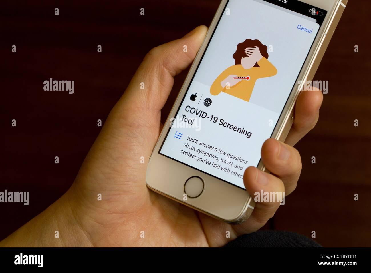 Una donna usa l'app COVID-19 di Apple Inc. Sul suo iPhone. L'app raccoglie tutto ciò che riguarda il coronavirus e consente agli utenti di controllare i sintomi. Foto Stock